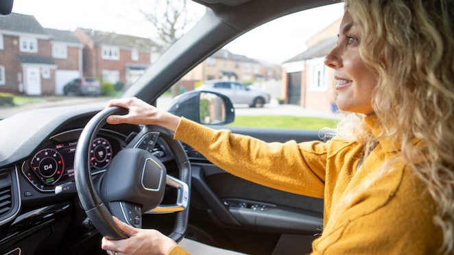 Woman in car driving and smiling