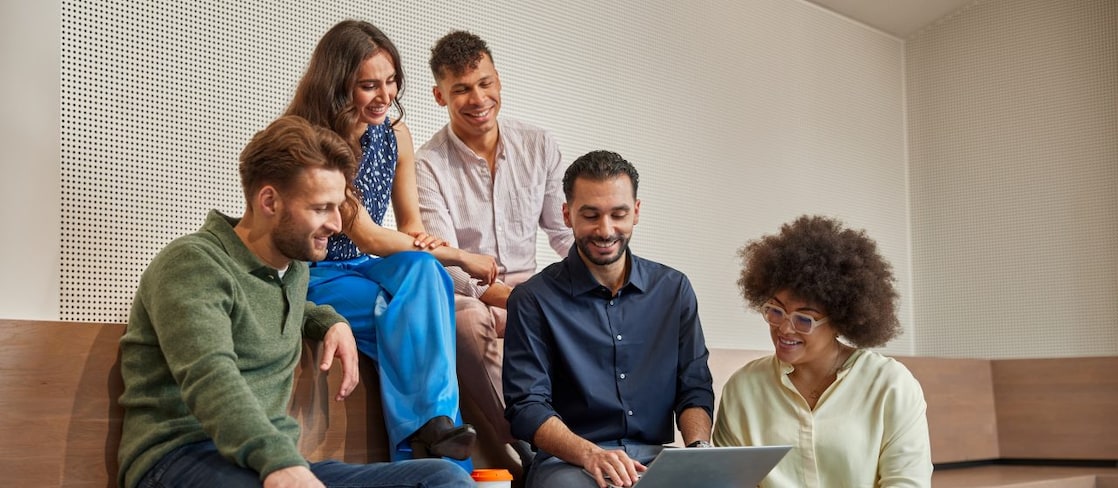 Five people sit on wooden steps in smart casual attire