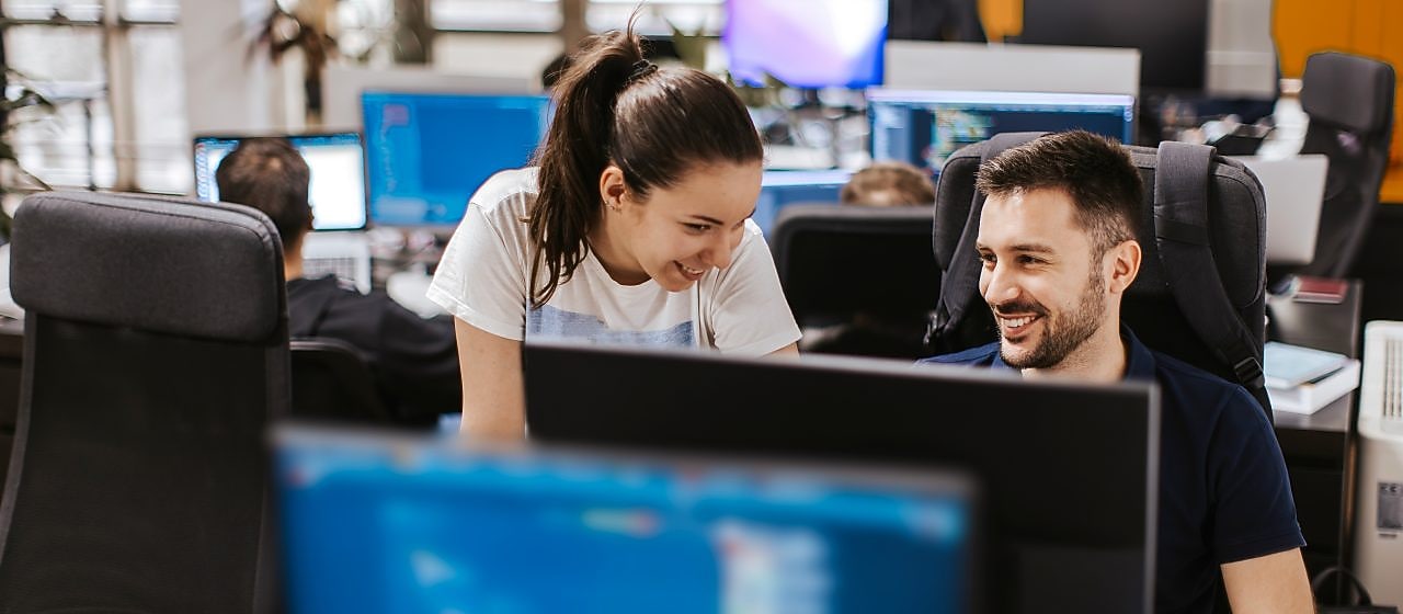 Two colleagues collaborating at a computer workstation in a office