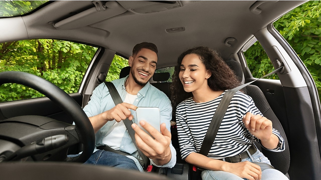 Man and woman looking at a phone in a stationary car