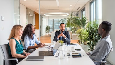  Smiling man with a headset in an office setting, looks at a computer screen