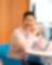 A joyful person in a light pink shirt sits at a round table with a laptop