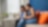 Two women sit on a couch in a modern office, engaged in discussion over a laptop