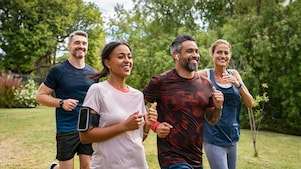 Four people jog in a park, all smiling and energetic