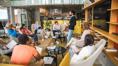 A diverse group sits in a cozy, modern office, engaging in a lively meeting