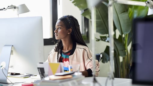 Side portrait of african american woman sitting in front of the computer surrounded by plants.