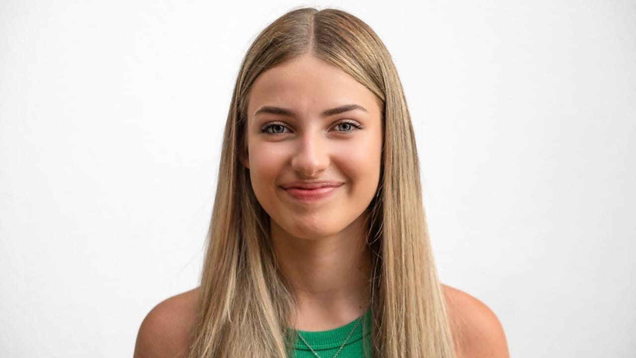Corporate front portret of a smiling young woman in green top with long blond hair.