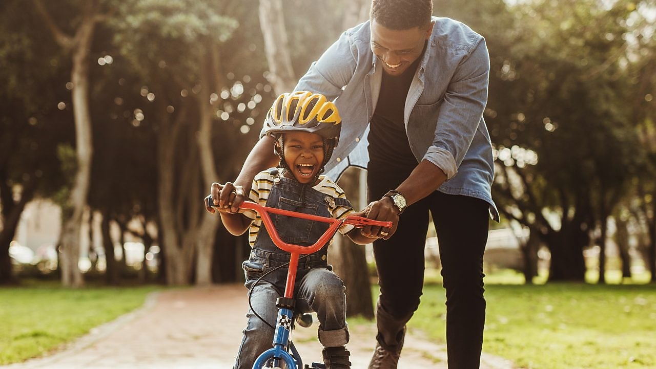 father teaching his son cycling at park