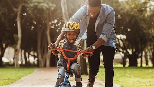father teaching his son cycling at park