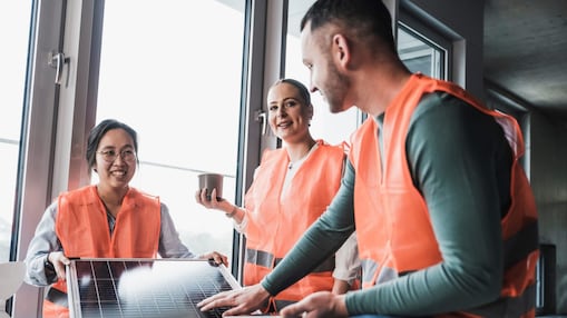 Engineers wearing reflective clothing with solar panel at office