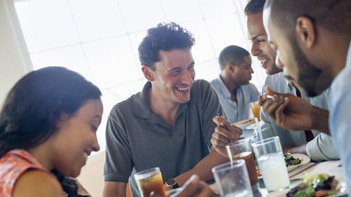 A group of friends are laughing and smiling while they enjoy a meal out together