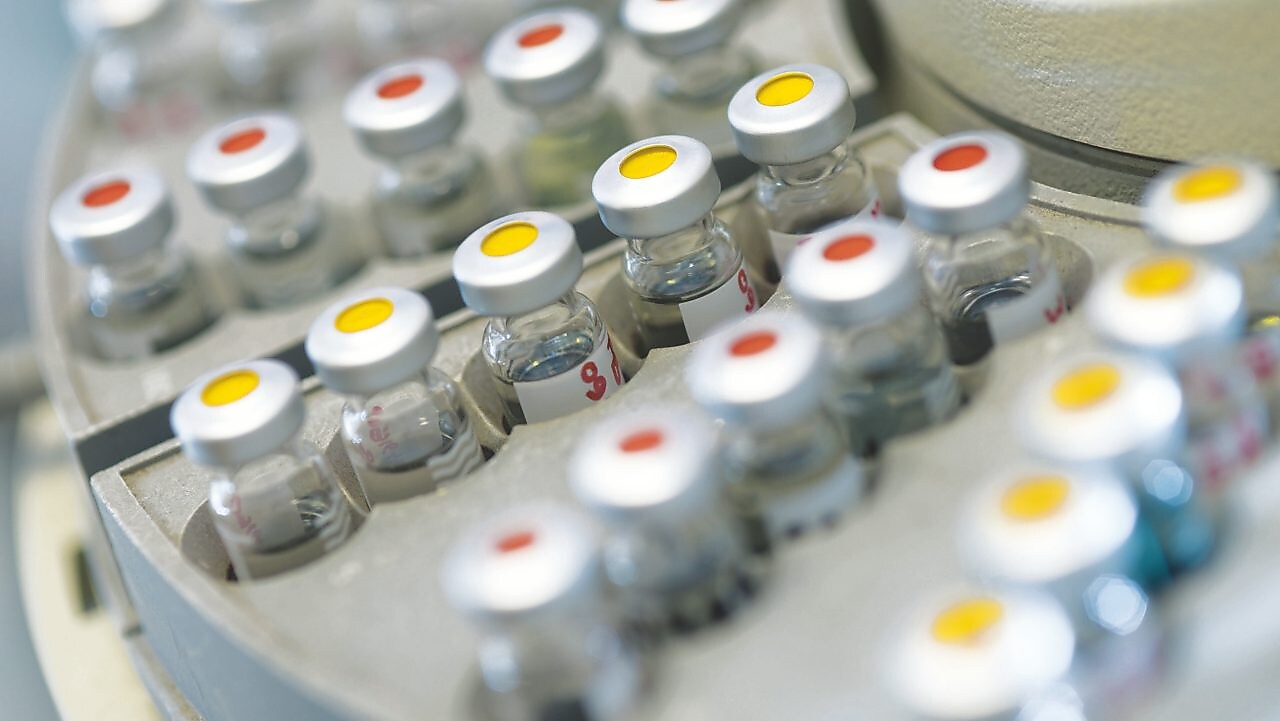 Rows of medicine vials sitting in a holder, some with red dots on the lid, and some with yellow dots on the lid