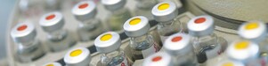 Rows of medicine vials sitting in a holder, some with red dots on the lid, and some with yellow dots on the lid