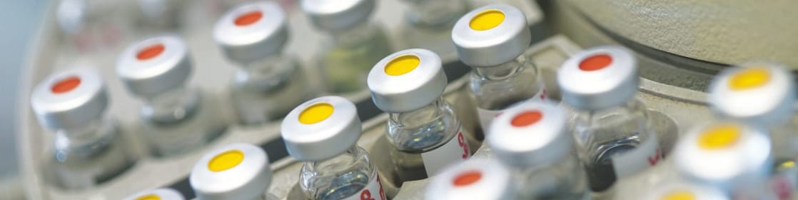 Rows of medicine vials sitting in a holder, some with red dots on the lid, and some with yellow dots on the lid