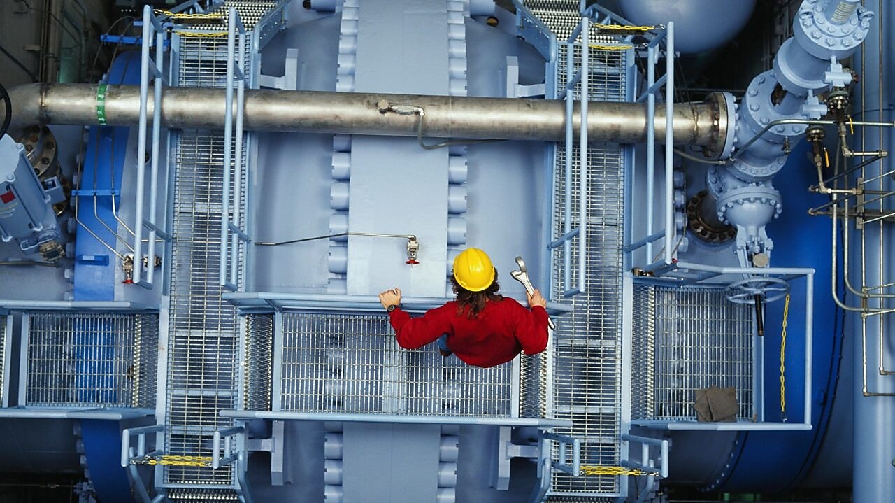 Worker inspecting valve at power station