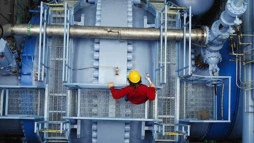 Worker inspecting valve at power station