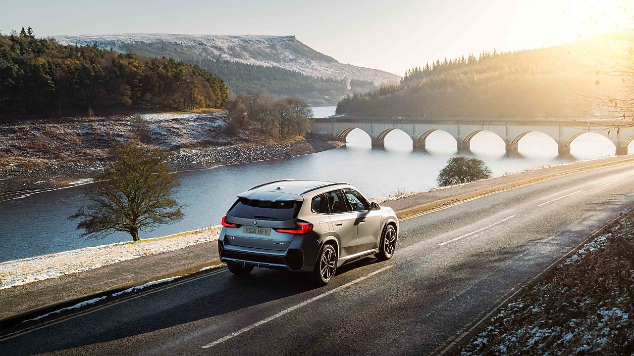 A car driving on a riverside road in a snowy landscape