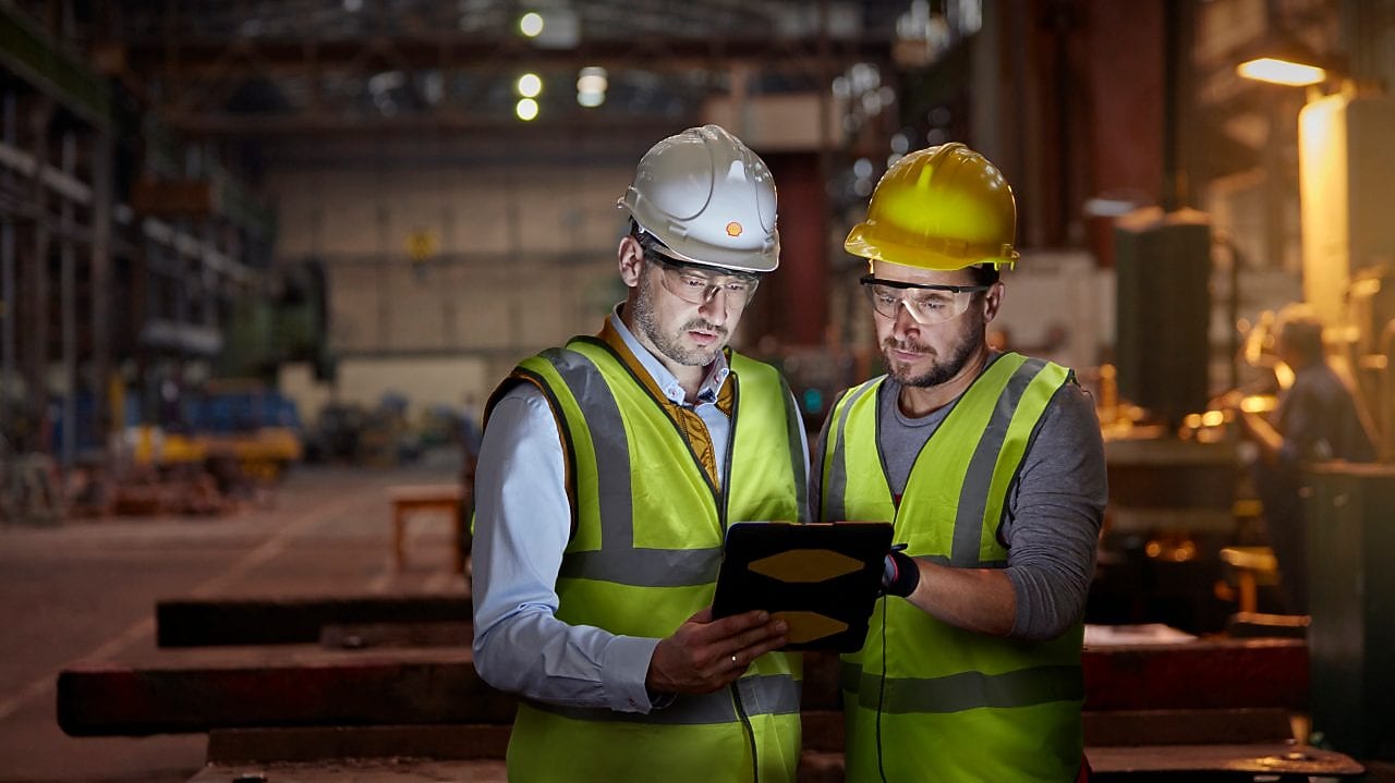 Engineer and worker using digital tablet in dark factory