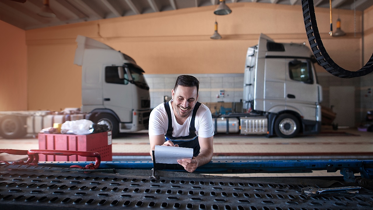 Truck mechanics doing paperwork before vehicle service in truck repair shop