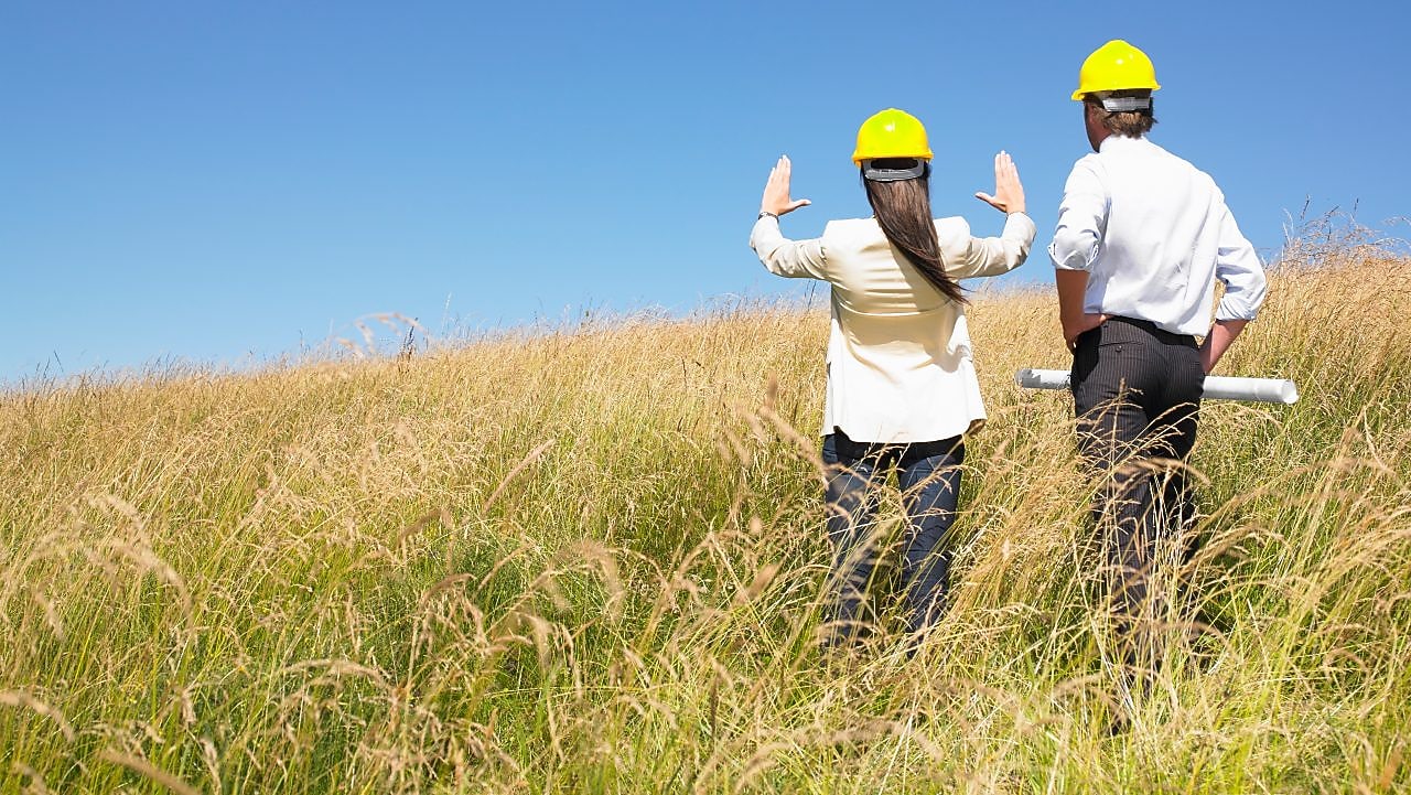 Two workers in hard hats overlooking a field