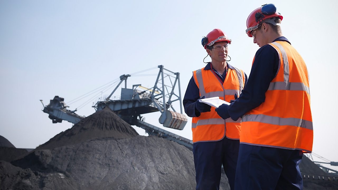 Two workers in high visibility jackets and hard hats in a mine
