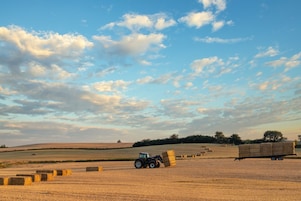 Farmer collecting hale bales with a tractor on his farm