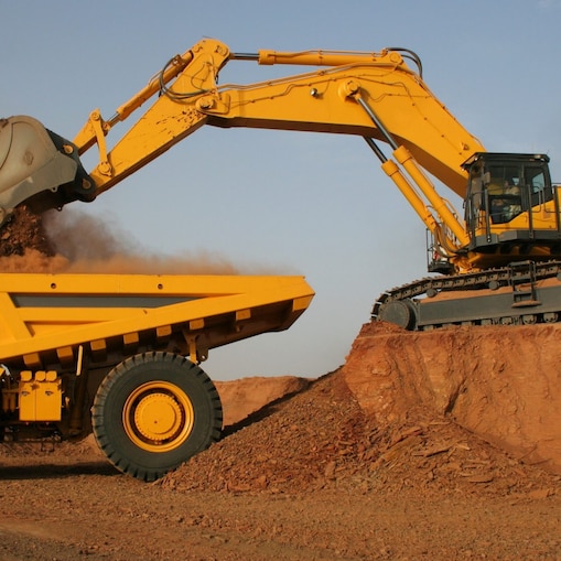 Digger dumping earth into a dump truck
