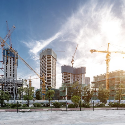 Urban construction site with multiple high-rise buildings in progress, surrounded by several tall cranes.