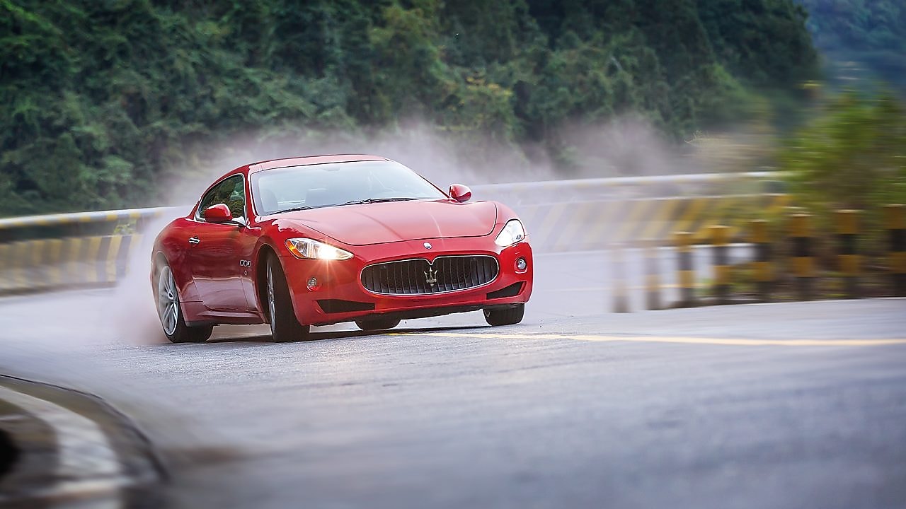 Red maserati climbing up mountain-road