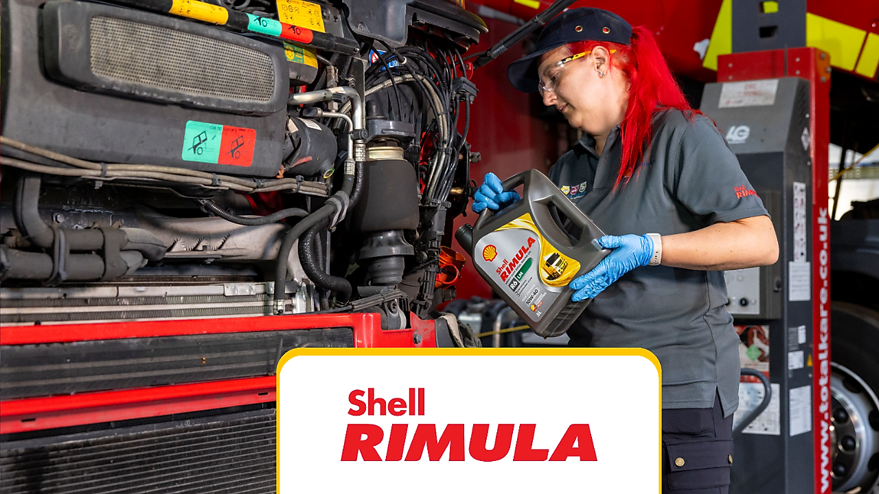 In auto repair shop – pouring oil into a truck.