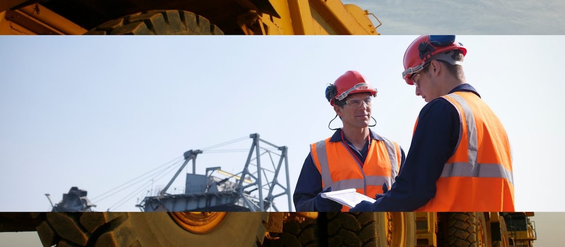Two workers in high visibility jackets and hard hats in a mine 