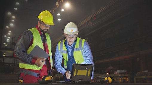Two engineers in hard hats viewing information on tablets