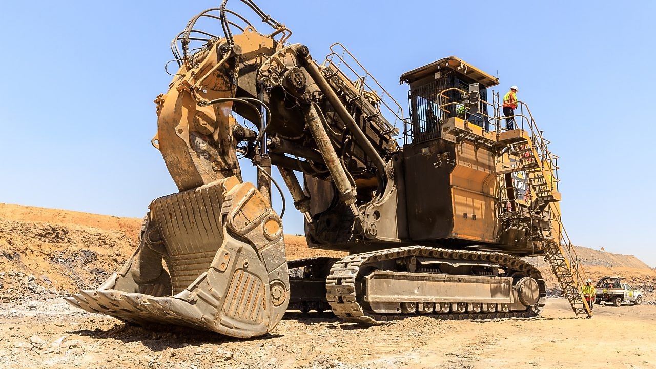 Large excavator in a mine with engineers working on it
