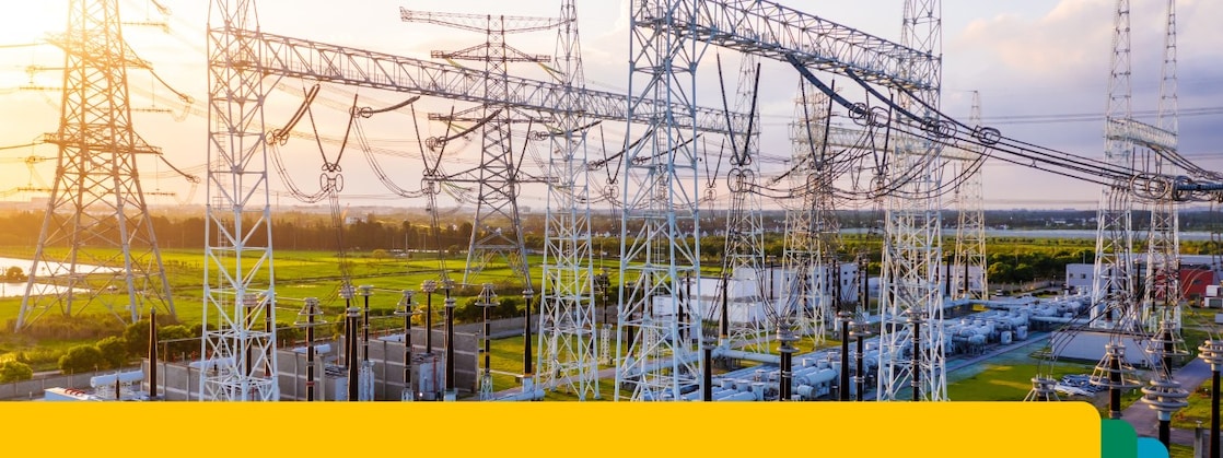 Electrical power substation with interconnected high-voltage transmission lines and equipment at sunset.