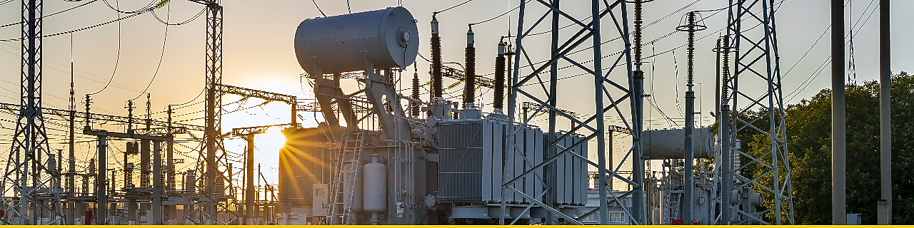 Electrical power substation with interconnected high-voltage transmission lines and equipment at sunset.