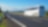 White Bus driving on an empty road in a rural landscape. Villages and forested mountains in the background.