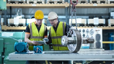 Engineers reviewing industrial equipment and gear systems in a manufacturing facility, supported by Shell expertise in machinery reliability and lubrication solutions.