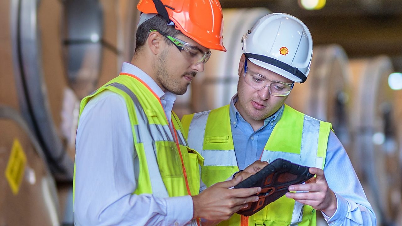 Two Shell employees studying a tablet in factory
