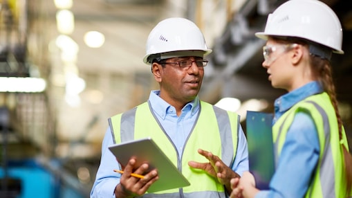Two engineers in high vis jackets studying tablet