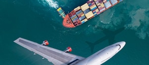 Aerial view of a plane flying past a cargo ship that was leaving the harbor, with a truckboat spinning a large ship.