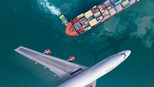 Aerial view of a plane flying past a cargo ship that was leaving the harbor, with a truckboat spinning a large ship.