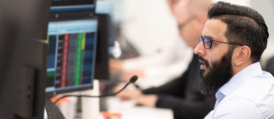 Professional monitoring energy market pricing and electricity trading data in a control room.