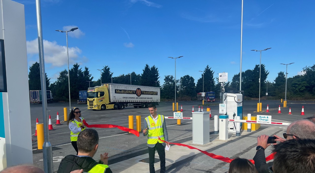  One person cutting a red ribbon another person is holding.