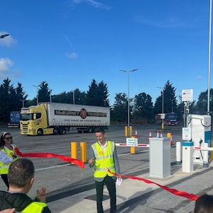  One person cutting a red ribbon another person is holding.
