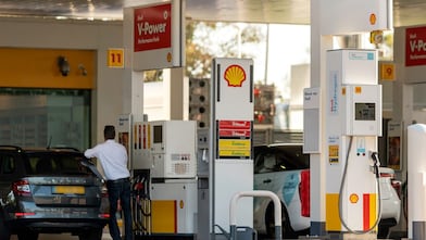 Shell forecourt showing V-Power petrol pumps and a Shell Hydrogen dispenser beneath a canopy, with two cars refuelling.