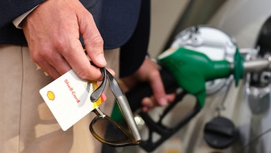 Close-up of a person in high-visibility clothing unplugging an electric vehicle charging connector from the unit.