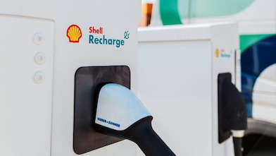 Close-up of a Shell Recharge electric vehicle charging unit with charging connector inserted into the socket.