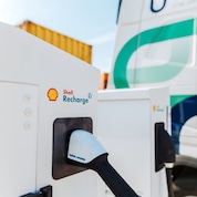 Close-up of a Shell Recharge electric vehicle charging unit with charging connector inserted into the socket.