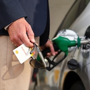 Close-up of a person in high-visibility clothing unplugging an electric vehicle charging connector from the unit.