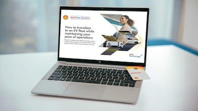 Laptop on desk displaying Shell Fleet Solutions webpage about transitioning to an EV fleet, with Shell Card placed on keyboard.